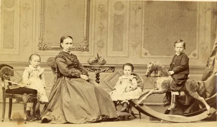 Jeune garçon sur un cheval à bascule entouré de sa famille, années 1860